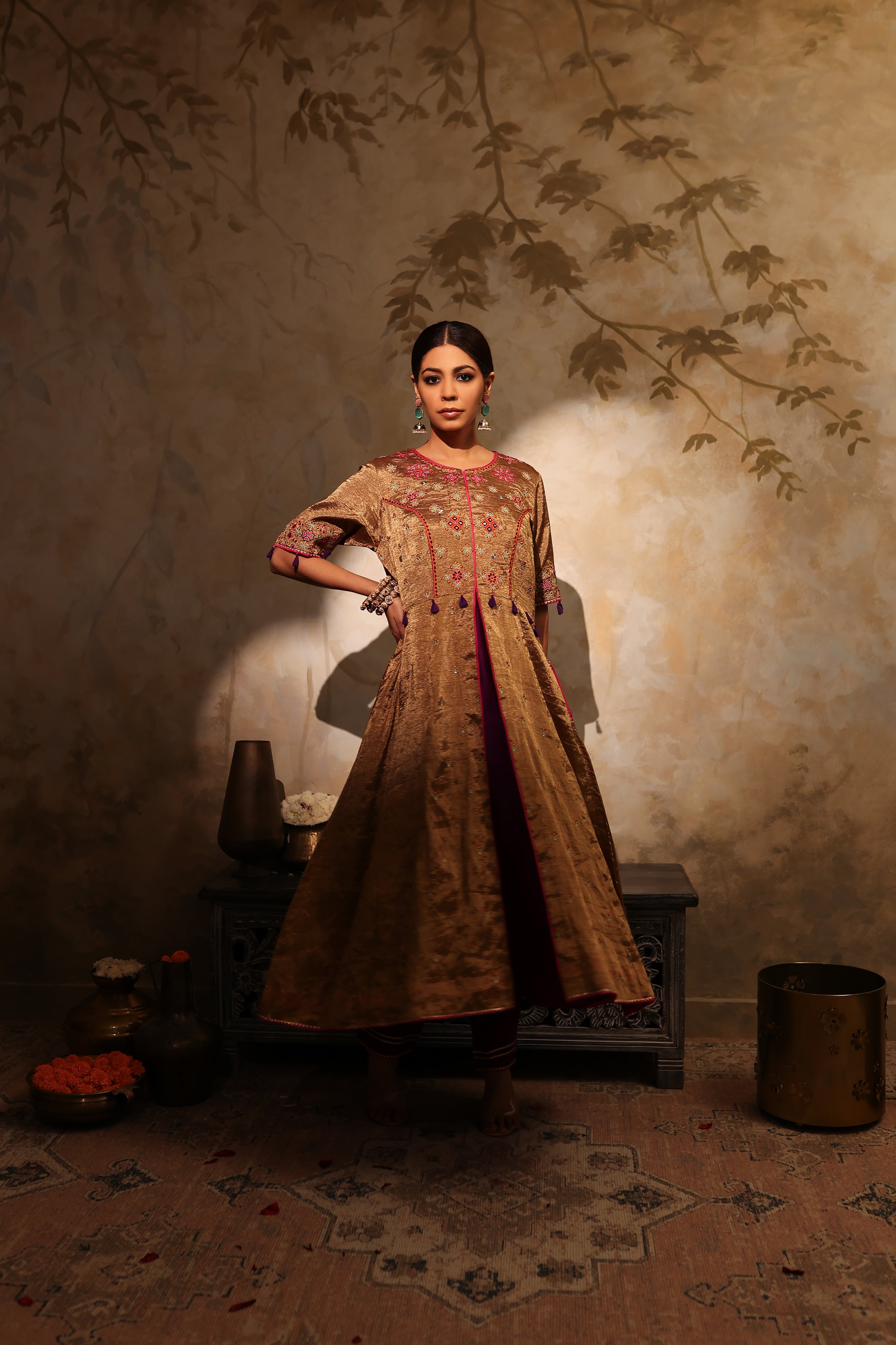 Model wearing a golden silk tissue embroidered jacket-style kurta with tassel details, paired with a plum underlayer and matching pants—luxury festive and wedding outfit.