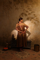 Model wearing a golden silk tissue embroidered jacket-style kurta with tassel details, paired with a plum underlayer and matching pants—luxury festive and wedding outfit.