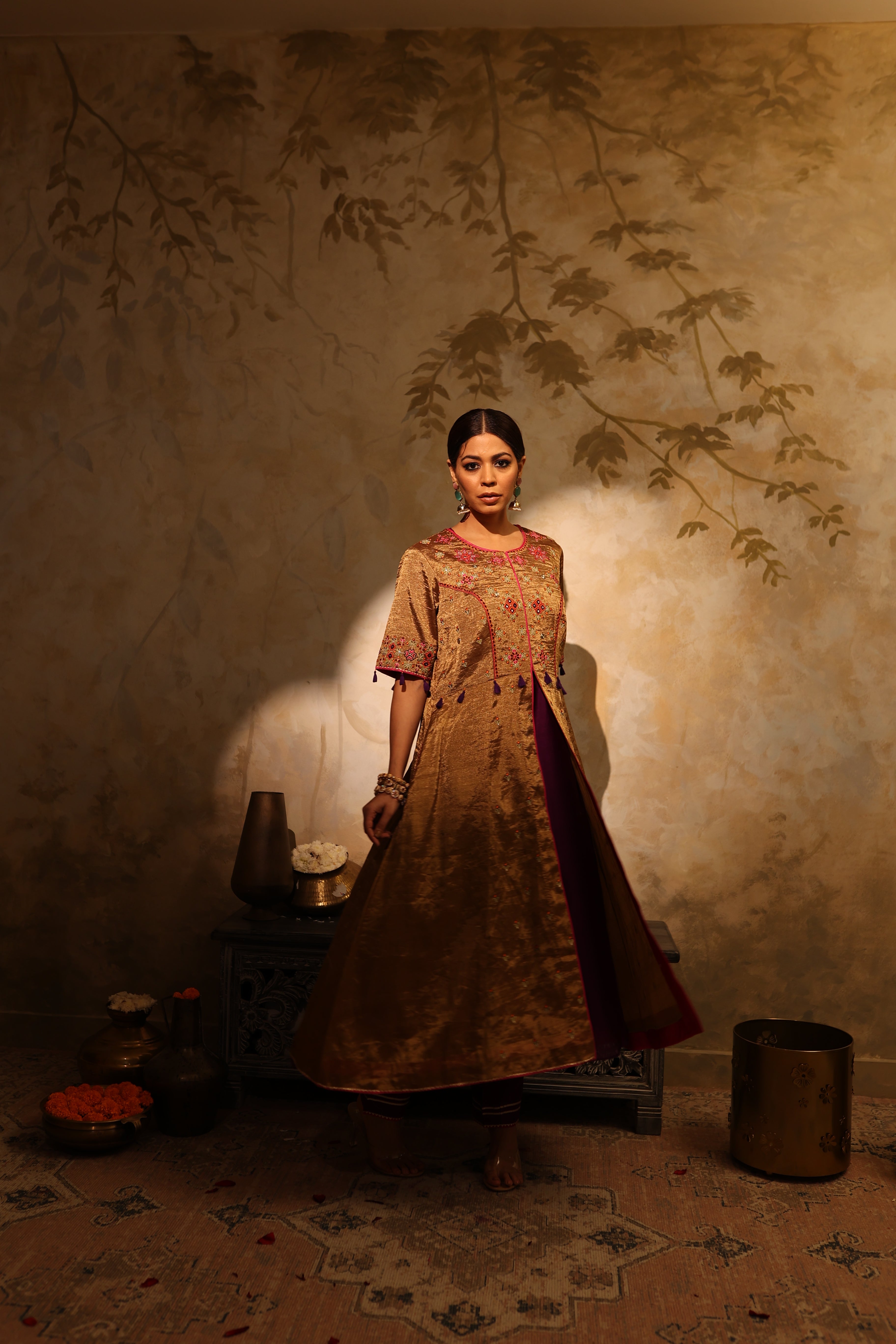 Model wearing a golden silk tissue embroidered jacket-style kurta with tassel details, paired with a plum underlayer and matching pants—luxury festive and wedding outfit.
