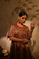 Model wearing a golden silk tissue embroidered jacket-style kurta with tassel details, paired with a plum underlayer and matching pants—luxury festive and wedding outfit.