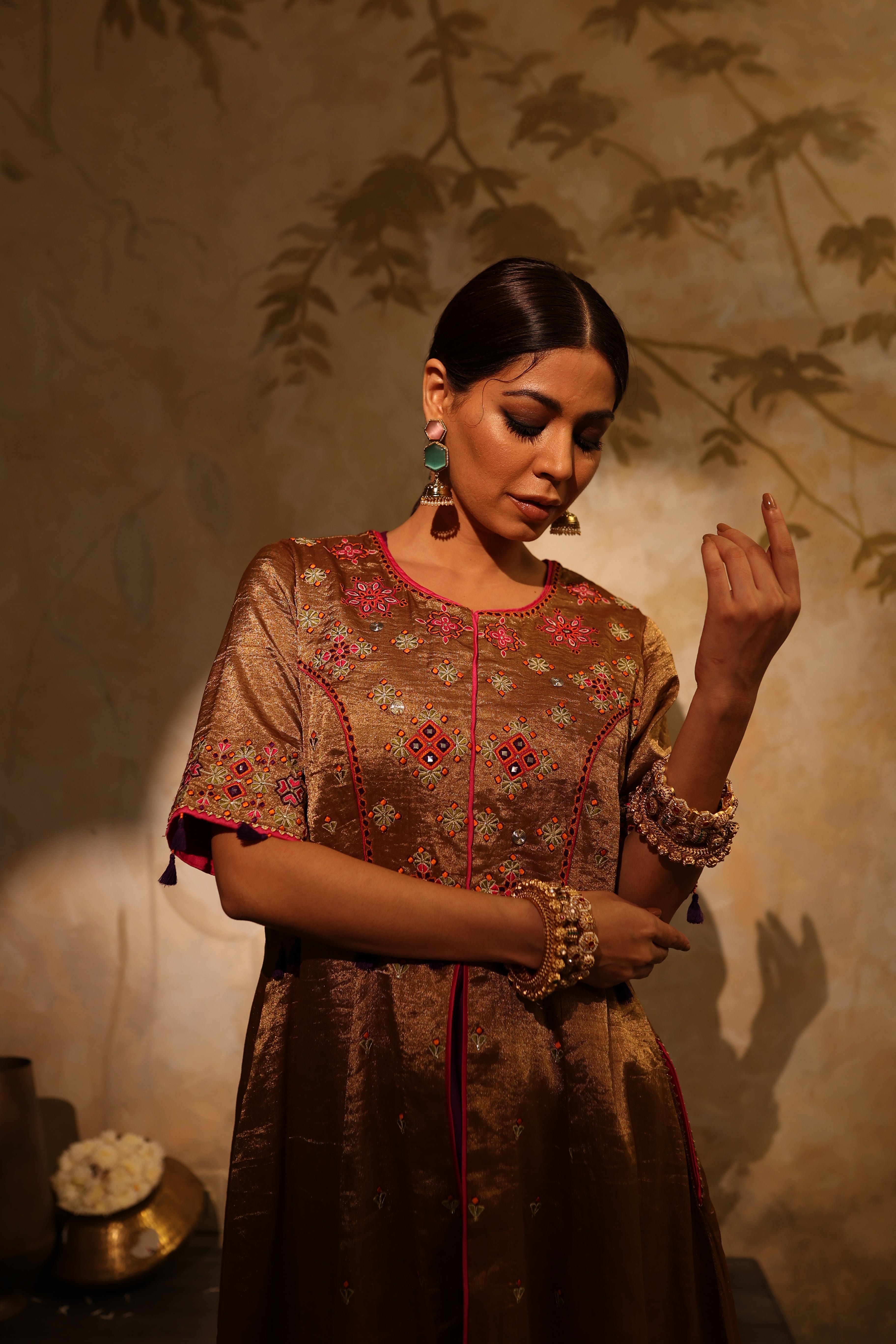 Model wearing a golden silk tissue embroidered jacket-style kurta with tassel details, paired with a plum underlayer and matching pants—luxury festive and wedding outfit.