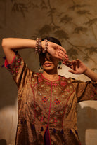 Model wearing a golden silk tissue embroidered jacket-style kurta with tassel details, paired with a plum underlayer and matching pants—luxury festive and wedding outfit.
