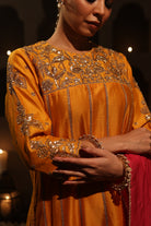 Model wearing an orange silk chanderi kurta set with pink dupatta, adorned with gold zari hand embroidery — festive wedding outfit.