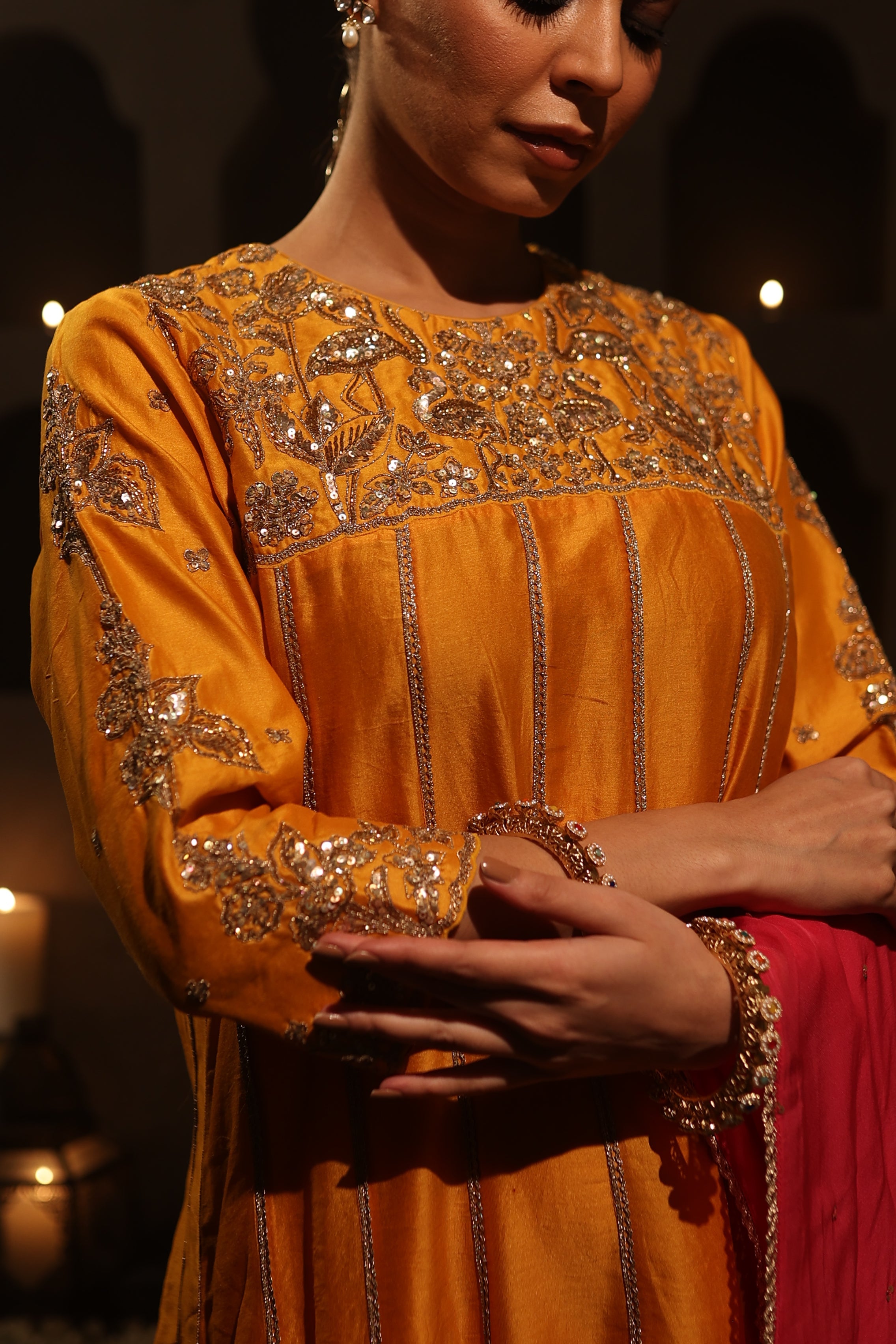 Model wearing an orange silk chanderi kurta set with pink dupatta, adorned with gold zari hand embroidery — festive wedding outfit.