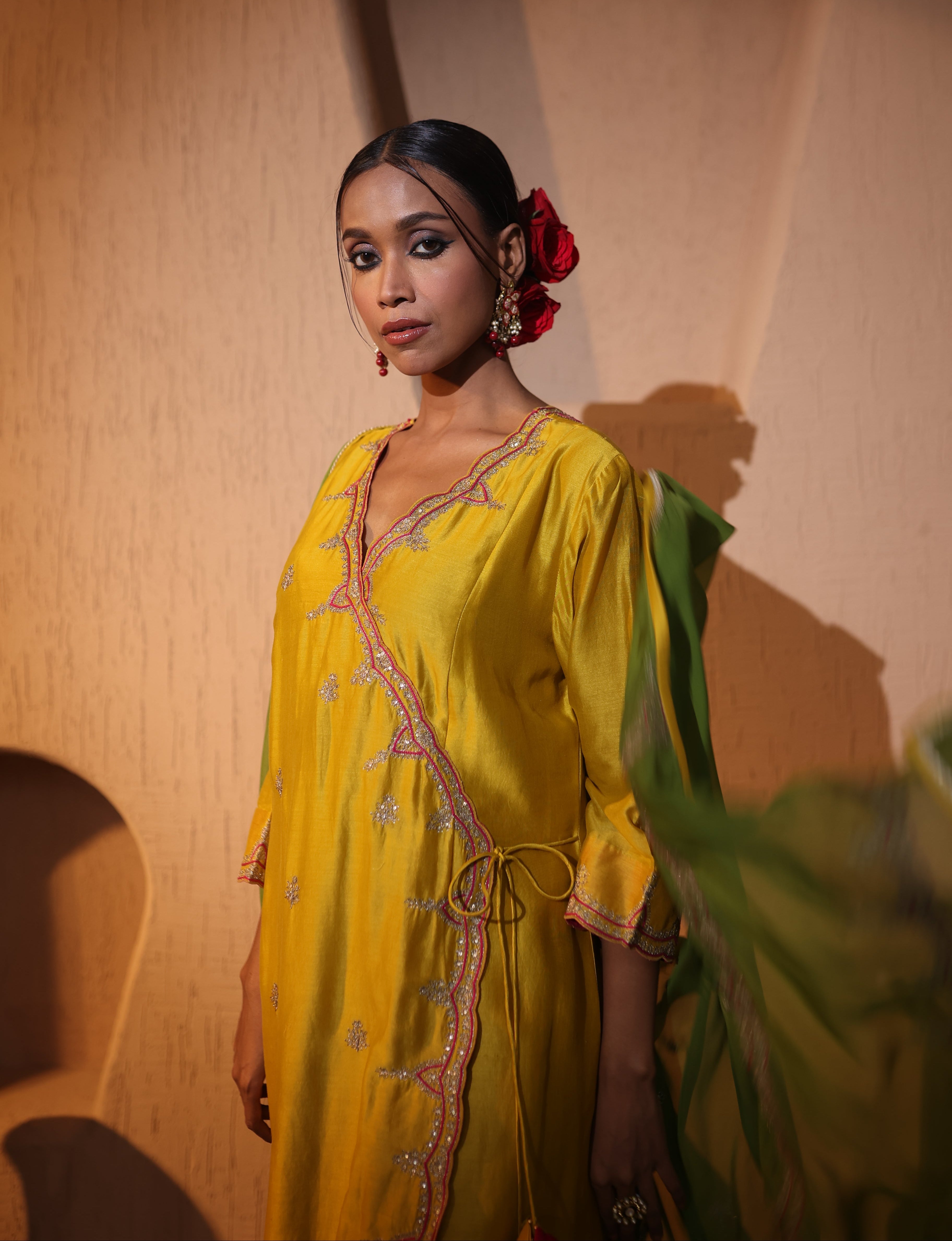 Model wearing a yellow silk chanderi kurta set with green dupatta, red pants with tassel and gold zari aari taari hand embroidery — festive ethnic outfit.