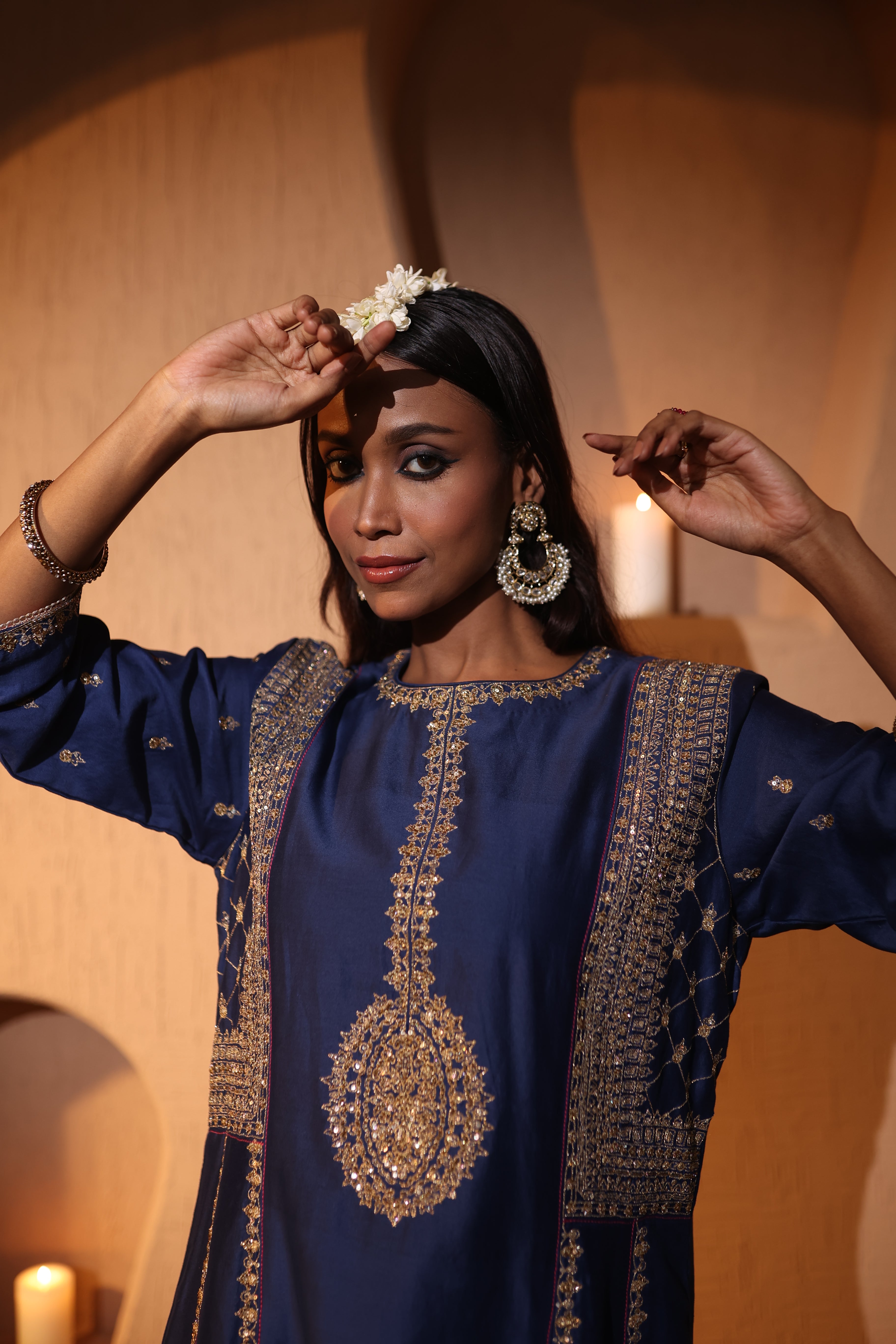 Woman wearing a blue embroidered silk chanderi kurta set with gold zari hand embroidery details, posing indoors.