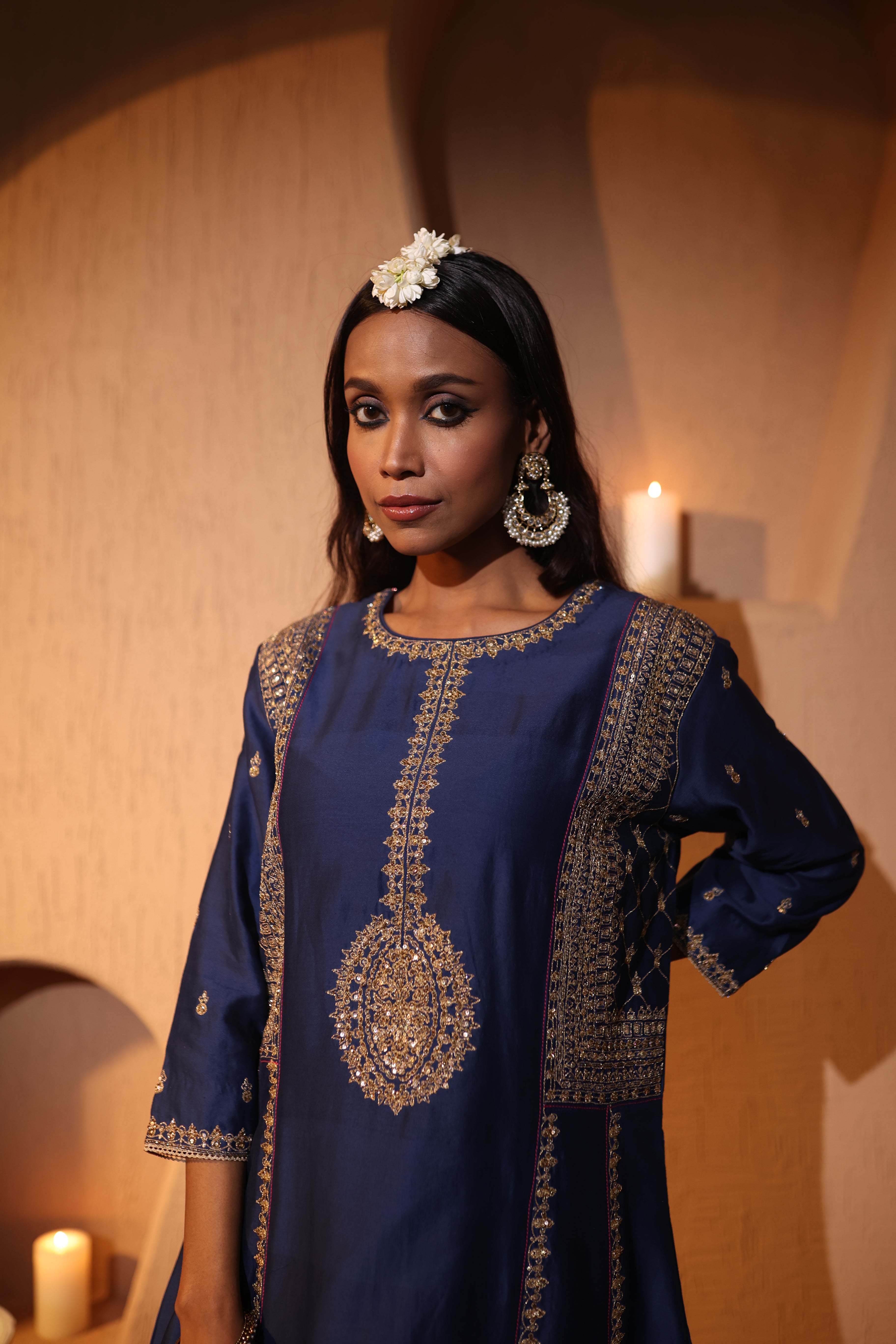 Woman wearing a blue gold zari hand embroidered kurta set in a warm-toned room. 
