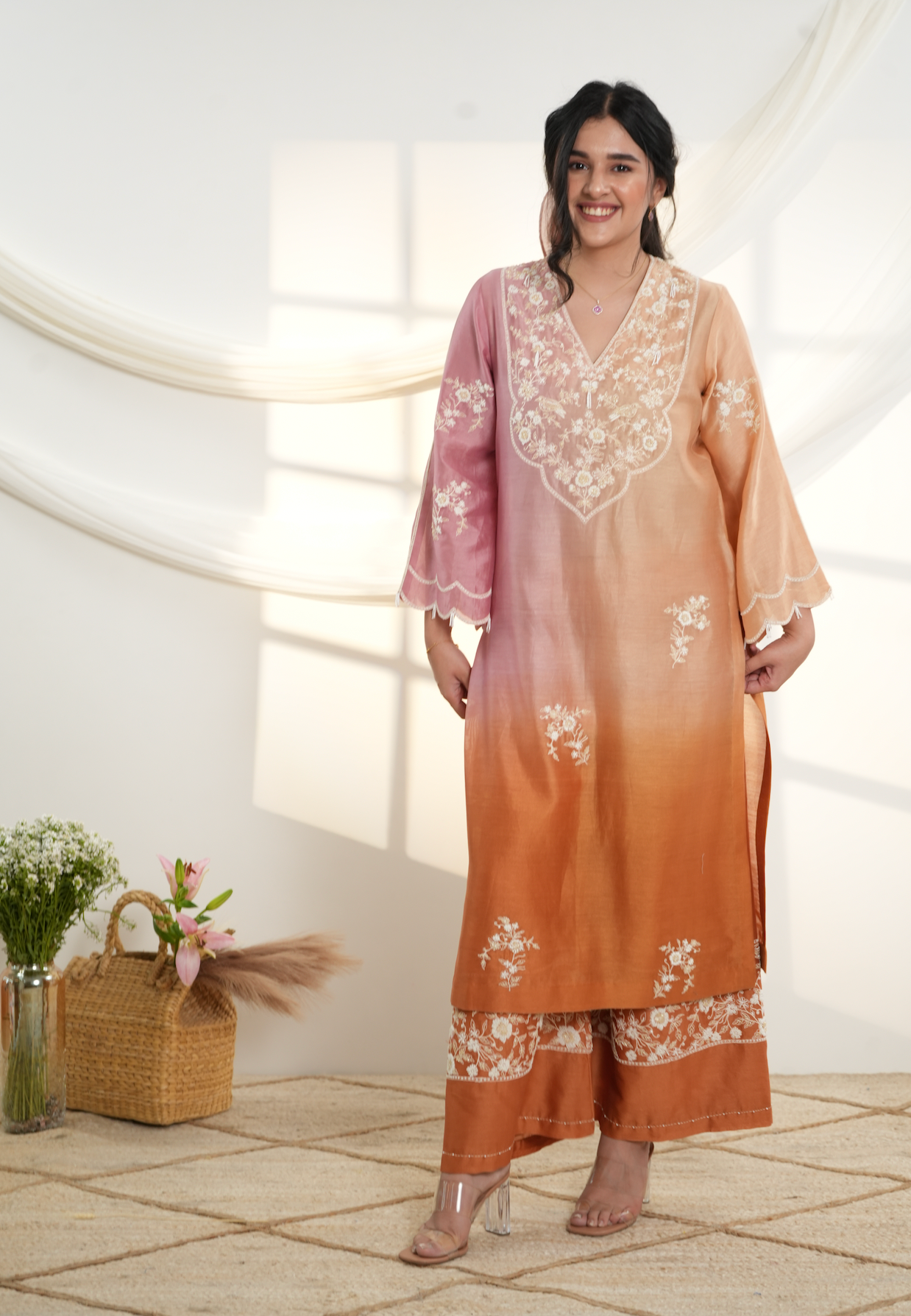 Model wearing a peach & pink ombre silk chanderi kurta set with off-white dori and bead embroidery, styled with floral embroidered wide-leg pants.